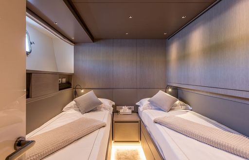 Twin guest cabin onboard charter yacht JICJ, single beds to either side with a small hull window