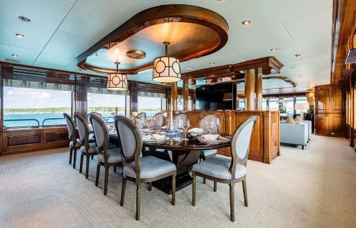 Interior dining area onboard superyacht charter REMEMBER WHEN, long table surrounded by gray upholstered seats