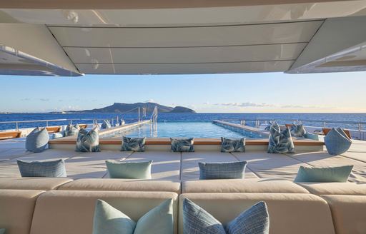 Overview of the aft deck onboard superyacht charter RENAISSANCE, with a large infinity pool and many sun pads