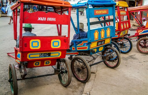 A red and a blue pedal taxi seen from behind