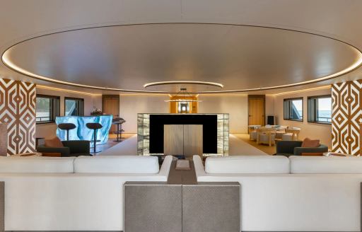 Interiors onboard charter yacht LA DATCHA with white sofas forward and a wet bar in the background