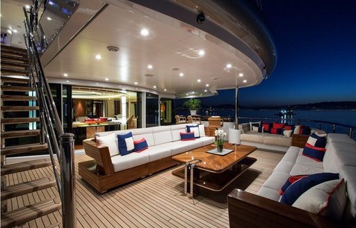 Nightime view of outdoor lounge area with white sofas on superyacht Arience