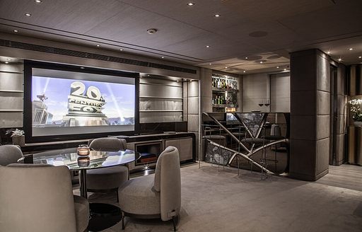Cinema area onboard charter yacht SEVERIN'S, large wall-mounted TV screen with a round table and chairs in the foreground 