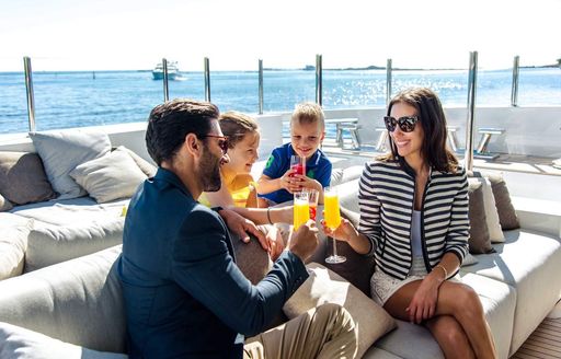a family of rich peopel enjoying oj on their luxury charter yacht so that they can boost their immune system in these imminent times 