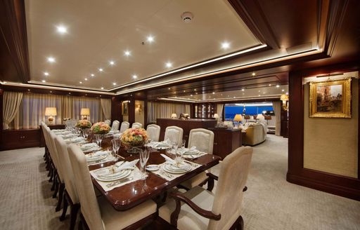 Interior dining set up with long table and cream upholstered chairs onboard private charter yacht GIGIA