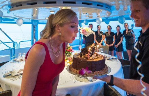 A guest blows out candles on her birthday cake on a yacht
