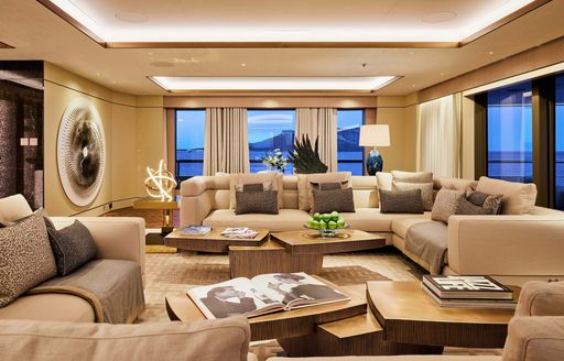 Interiors onboard superyacht charter RENAISSANCE, plush lounge area with cream seating and full-height windows