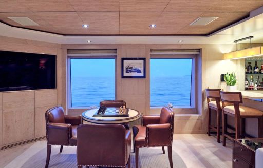 Games table and adjacent wet bar in the upper salon onboard charter yacht TIMBUKTU