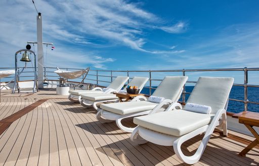 Sunloungers on the deck of motor yacht Sherakahn under a blue sky