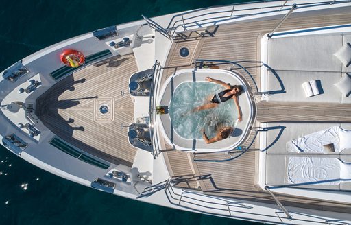 Overhead view looking down on the deck Jacuzzi onboard charter yacht HAPPY ME, with two charter guests enjoying the Jacuzzi