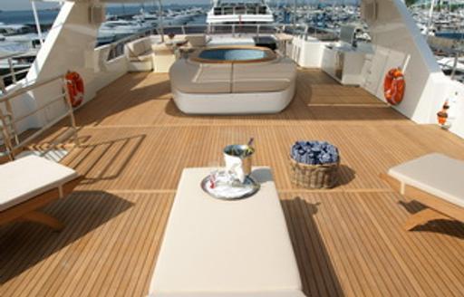 Overview of the sun deck onboard charter yacht TATIANA I, sun loungers in the foreground with a deck Jacuzzi aft