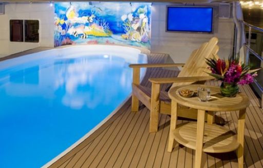 pool on sundeck of luxury charter yacht global, with tv screen and chair
