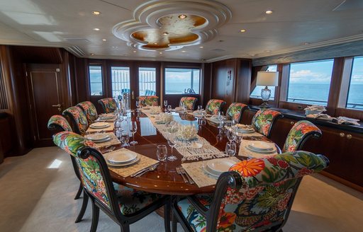Formal dining area onboard charter yacht NEVER ENOUGH, central dining table with 12 seats, surrounded by windows
