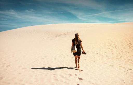 A woman walks bare foot along the shifting sand dunes of Rabjerg Mile in North Jutland, Denmark