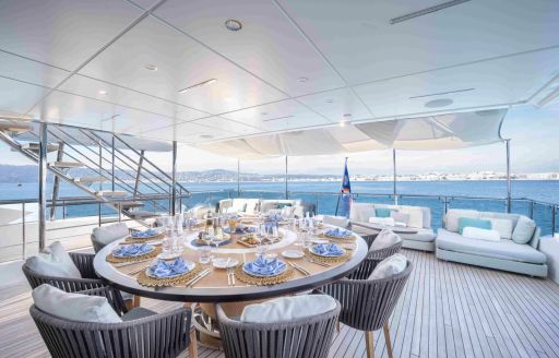 Alfresco dining setup onboard boat charter CHARADE, circular table with sofas in the background