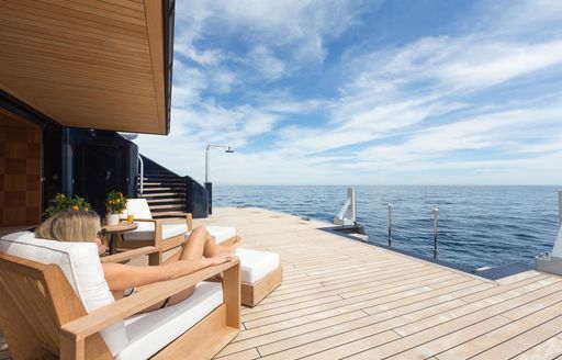 beach club on superyacht luna, with woman lying on sunlounger