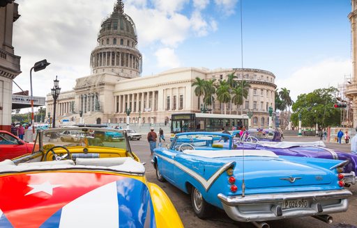 vintage car with Cuban flag on bonnet parks up in Cuban capital of Havanna