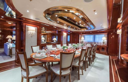 Interior dining room onboard charter yacht JOIA THE CROWN JEWEL, long table surrounded by cream upholstered chairs