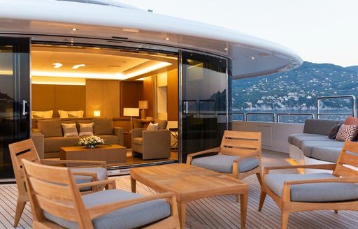 Exterior deck space onboard charter yacht ALFA, with grey upholstered chairs and a coffee table