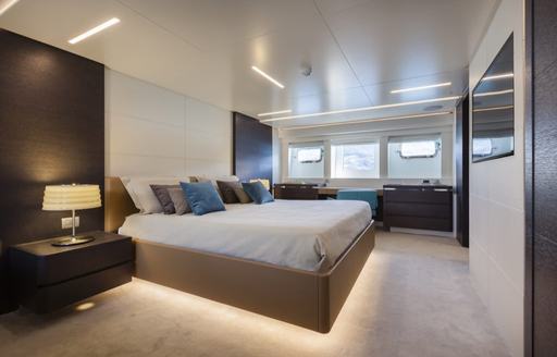 Master cabin onboard charter yacht 55 FIFTYFIVE, central berth facing a wall mounted TV and windows in the background