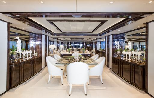 Interior dining area onboard charter yacht ILLUSION V, central dining table surrounded by white armchairs