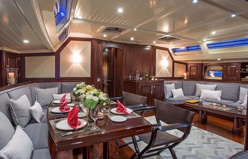 Dining table with lounging area opposite in main salon on board charter yacht Savarona