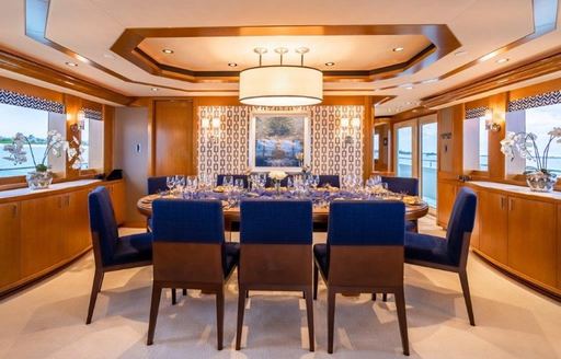 Formal dining area onboard charter yacht Far Niente, a long dining table surrounded by eight blue dining chairs