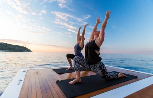 two women perform yoga on swim platform of motor yacht ‘QM of London’ 