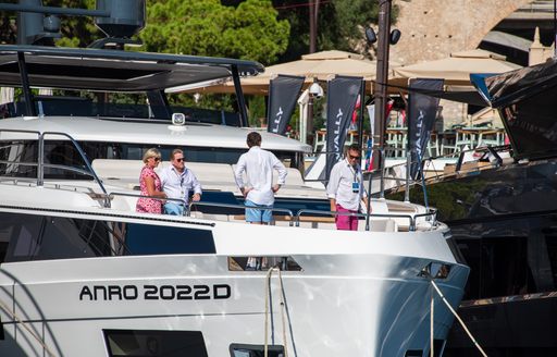Groupd of four visitors standing on the deck of a motor yacht at the Monaco Yacht Show
