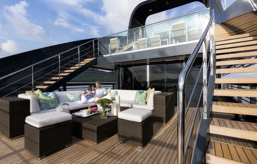 A man and woman relax on the exterior furnishings on board superyacht 'Ocean Emerald'