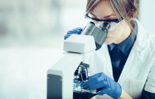 Scientist examines specimen under microscope