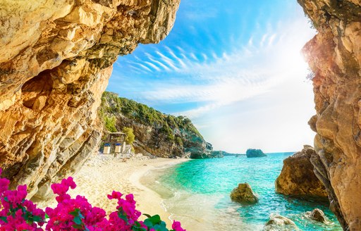 Quiet beach in Greece, with pink flowers around the opening of the cove