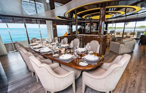 Interior dining area onboard charter yacht BABAS, formal set up with a long table surrounded by white upholstered seats