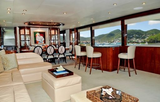 plush leather sofa, bar and formal dining table in Cherrywood-panelled main salon of charter yacht ‘Le Reve’ 
