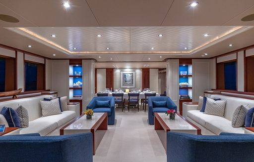 Interiors onboard charter yacht PISCES, white and blue seating arranged around the outside with dining area visible in the background