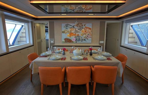 orange chairs surround the dining table in the main salon aboard superyacht ARCHSEA 