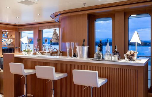 A wet bar with three white stools onboard charter yacht TREEHOUSE
