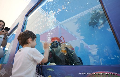 Close up view of the Dive Pool at the Dubai International Boat Show, young charter guest interacts with a diver