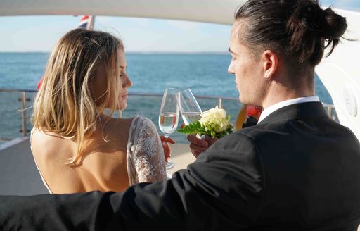 A wedding couple cheers with champagne on board charter yacht CHESS