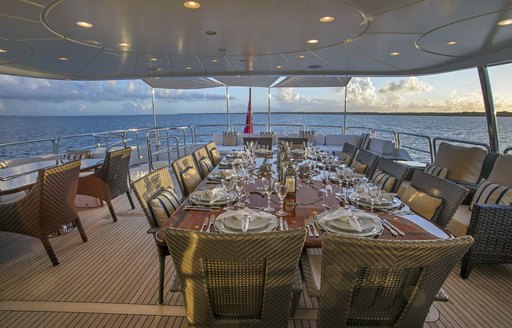 upper deck dining area on charter yacht pure bliss, with table laid formally and seating adjacent