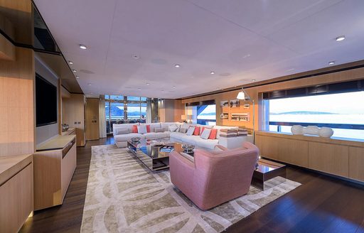Main salon lounge area onboard charter yacht MR T, comfortable white and pink seating with wide windows behind