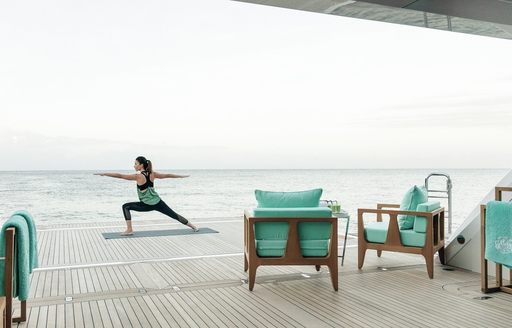 Woman doing yoga on expansive swim platform on board charter yacht Ramble on Rose