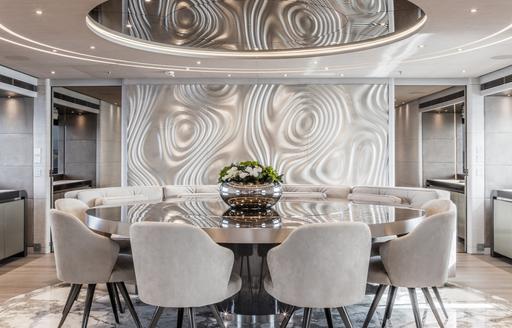 Formal dining area onboard charter yacht SEVERIN'S, circular table surrounded by chairs and large windows to starboard 
