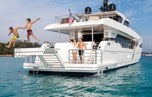 Charter guests jumping off the swim platform of luxury yacht ONEWORLD