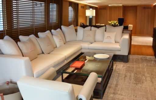 Main salon onboard charter yacht XIPHIAS, L-shaped white sofa and adjacent armchair