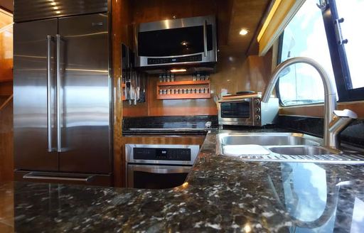 Galley onboard Charter yacht QARA, sink looking out through window with American style fridge 