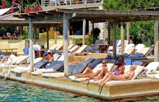 females sunbathe close to the ocean at Maçakizi beach club in Bodrum, Turkey