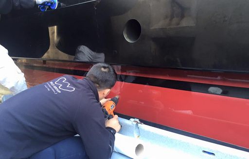 Worker from Wild Group applies film layer to exhaust area of superyacht Alfa Nero