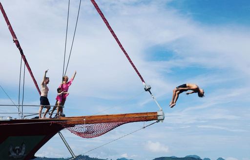 a guest jumps of the bowsprit while others look on on board sailing yacht ‘Orient Pearl’