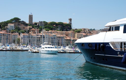 yachts moored in french harbour with buildings and hills in background